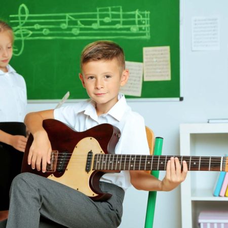 boy and girl in a classroom boy playing the guitar and g