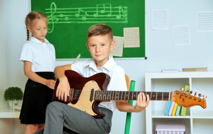 boy and girl in a classroom boy playing the guitar and g